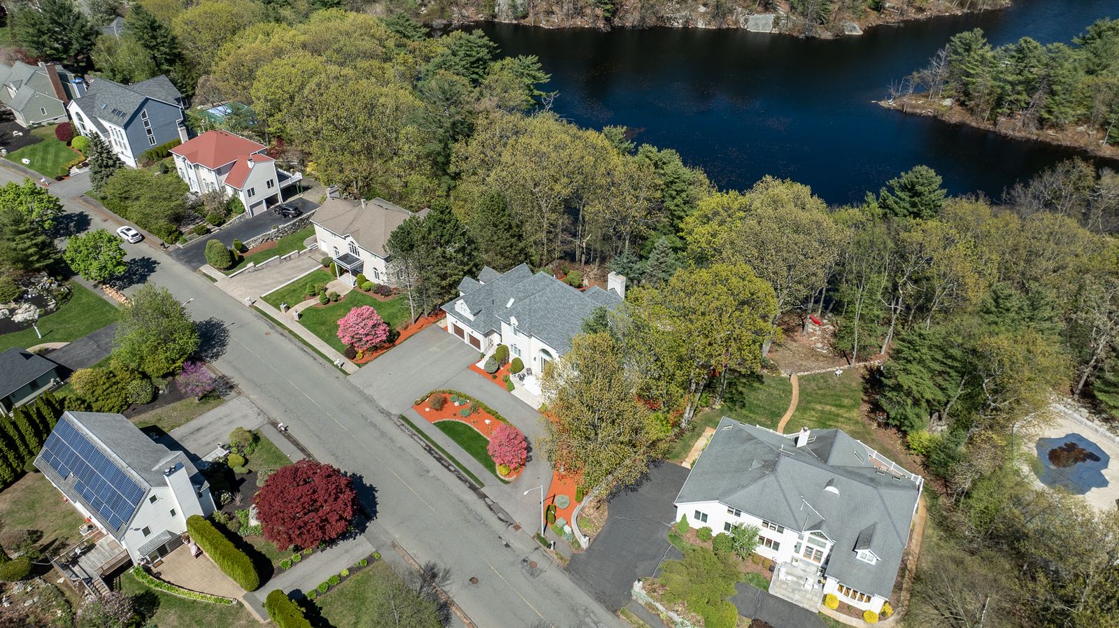 Aerial view of homes along a street by a pond